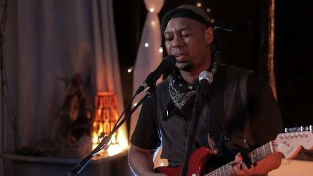 Picture of Desmond Sparrow Mase singing and playing guitar